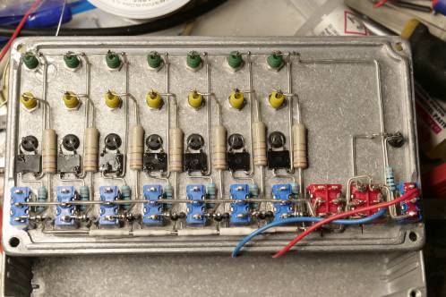 Meerdere electronica-onderdelen (weerstanden, diodes, schakelaars, LEDs en gelijkrichters) netjes recht en hoekig bedraad, gemonteerd in een aluminium deksel