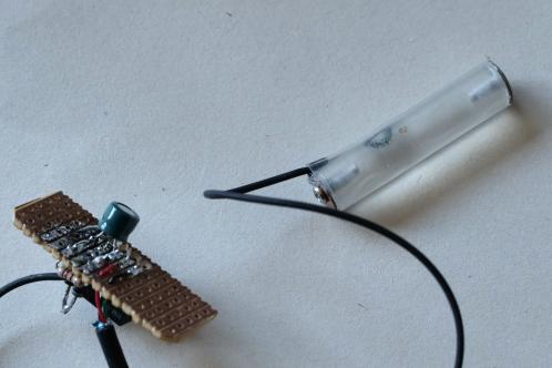 A small PCB with some components and a piece of acrylic round rod covered in heatshrink