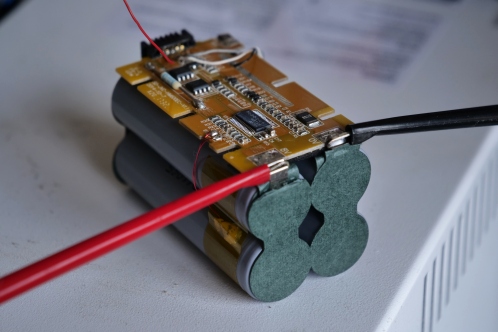 Een elektronicaprint, 4 lithium-cellen en 2 meetklemmen om de lithium-cellen op te laden met een labvoeding