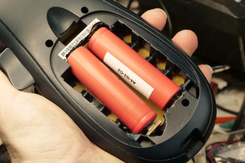 Twee rode cilindervormige lithium-cellen in een donkerblauwe behuizing geplaatst, het voormalige AA batterijvak van een Dymo Letratag