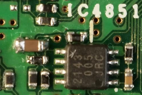 Een zwart op-amp SMD IC en diverse andere SMD componenten op een groene printplaat na hersolderen op het analog board van een JVC-GY-HM100 videocamera