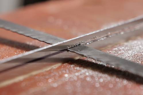 Een zaagblad in een gezaagde sleuf in de aluminium koelplaat van een LEDstrip