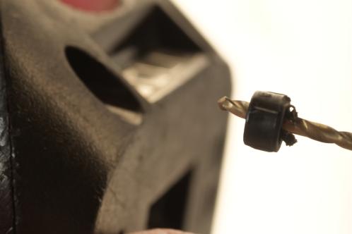 Een boor met zwarte kunststof plug, na verwijderen uit het verdiept liggende schroefgat van een Bosch PSR lithium schroefmachine-accu