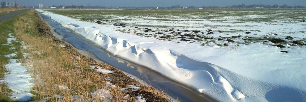 prachtig glooiende structuren van sneeuw die in open veld over de walkanten van sloten geblazen is en sneeuwduinen gevormd heeft