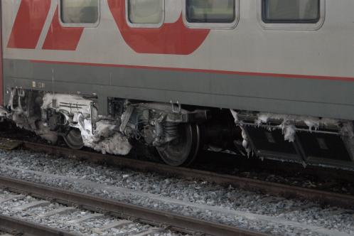 Enorme klompen ver-ijste sneeuw aan een buitenlands rijtuig van een internationale trein op A'dam CS