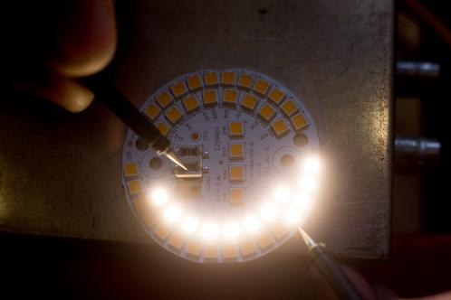 De cirkelvormige print met SMD LEDs gedeeltelijk brandend na aansluiting op een labvoeding, om defecte LEDs uit te sluiten