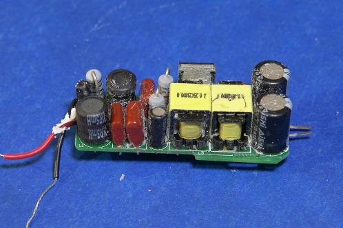 Dezelfde elektronicaprint gezien vanaf de andere zijde, met zeer diverse onderdelen (condensatoren, weerstanden, transistor, spoelen, elco's en een zekering) na het wegpulken van de grijze gietmassa