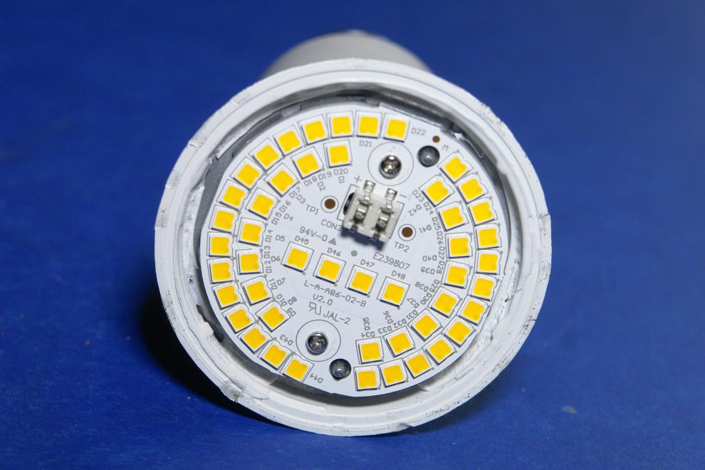 Een cirkelvormige aluminium print met 48 gele vierkantjes (SMD-LEDS), vastgeschroefd aan een koelblok met twee schroefjes