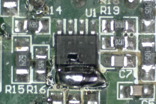 Een microscoopfoto van een groene elektronicaprint met een IW3689-01 SOIC-8 IC waarvan de pinnen 1 tot en met 4 verbonden zijn met 1 grote klodder tin ter verwijdering van het IC
