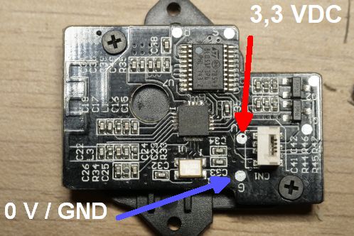 Een kleine zwarte printplaat met uitsluitend SMD-onderdelen in 0402 formaat, twee IC's, een antenne en connector voor verbinding met een andere print, de ontvangstmodule met A7105 IC van een Patona DMW-BGGH5RC batterygrip met de aansluitingen voor voeding gemarkeerd