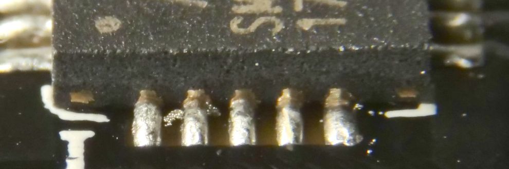 De zijkant van een IC (A7105) in QFN behuizing met zicht op de eerste 5 pinnen, met een mogelijke tinbrug tussen pin 1 en 2