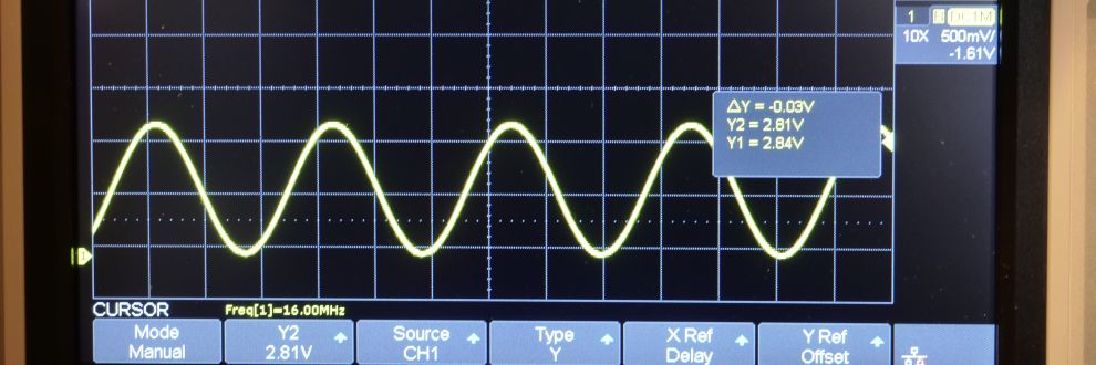Een zwart scoopbeeld dat een signaal (sinus) in gele lijn toont met een frequentie van 16 MHz, het vervormde kloksignaal van een 16 MHz oscillator, omdat een 100 MHz scoop dit niet juist weer kan geven