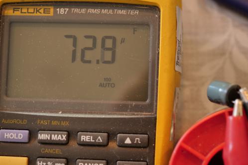 Een grijs LCD-display van een geel-grijze Fluke 187 multimeter geeft 72,8 uF aan voor een elco die 470 uF zou moeten zijn