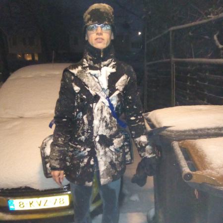 Een ondergesneeuwde auto en aan mijn zwarte jas en muts vastgeplakte sneeuw na fietstocht in sneeuwjacht op 10 december 2017